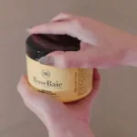 Femme appliquant le Trio Coco RoseBaie sur cheveux abîmés"