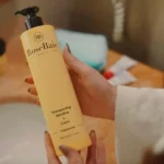 Femme appliquant le Trio Coco RoseBaie sur cheveux abîmés"